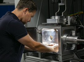 Ein Mitarbeiter von LaVa-X arbeitet an einer Laserschweißanlage mit der darin befindlichen offenen Evakuierungskammer, die in 3-5 Sekunden ein Vakuum über dem Bauteil erzeugt.