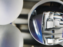 Auf der „5th Conference on Laser Polishing LaP 2022“ diskutieren internationale Fachleute neue Wege beim laserbasierten Polieren und Entgraten. Hier: Linse aus Quarzglas geschliffen (links) und laserpoliert (rechts). Durch die laserpolierte Linse ist ein laserpoliertes Bauteil aus Werkzeugstahl zu sehen.