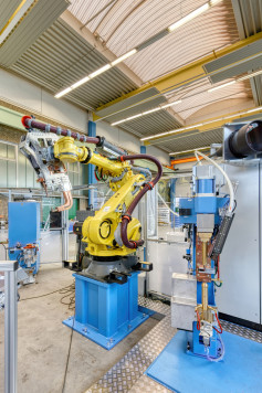 Ein Handling-Roboter führt das Bauteil zu einem DALEX-C-Modul. Dort werden die Rundschweißmuttern zugeführt und automatisch mittels Buckelschweißen auf dem Bauteil fixiert. / © DALEX GmbH