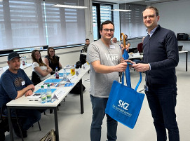 TZQ-Leiter Christoph Kreutz (rechts) übergibt den ersten Teilnehmern in den neuen Räumlichkeiten ein Willkommenspräsent