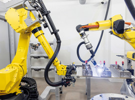 Roboterschweißzelle: WIG-Schweißen von sogenannten Hauptträgern, ein Handling-Roboter positioniert die Palette mit Bauteilen.
