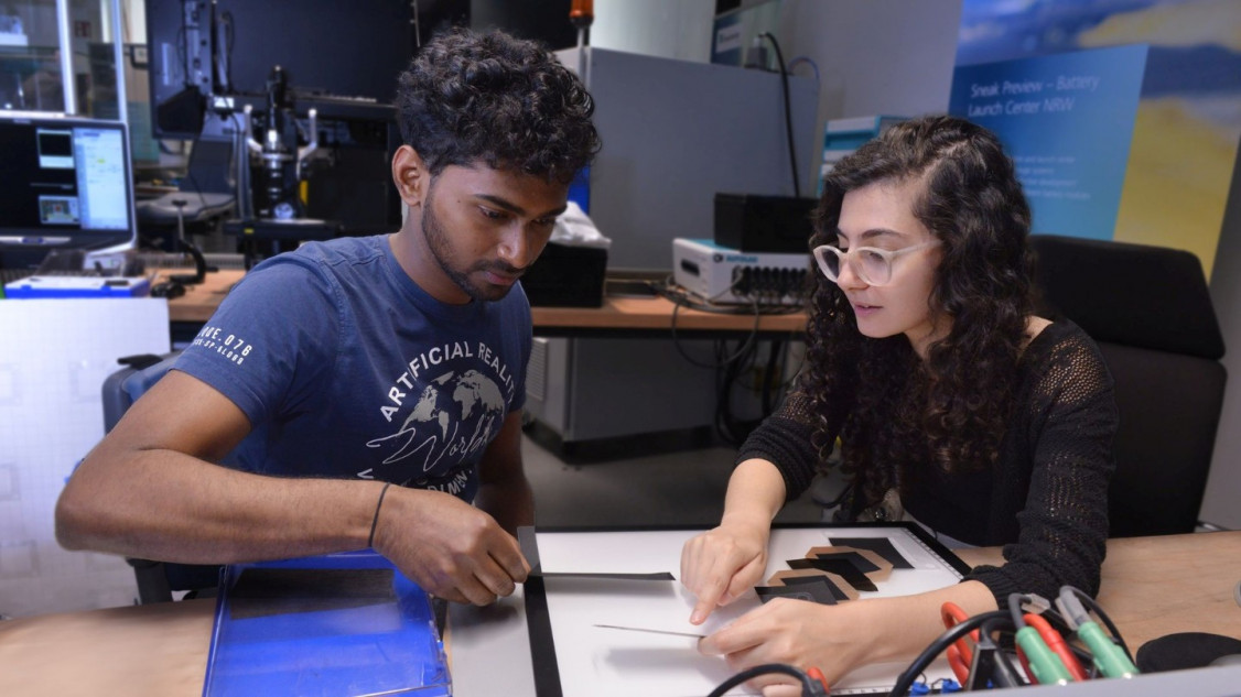 Sathishkumar Natarajan (links) und Manuella Guirgues vom Fraunhofer ILT arbeiten an der lasergestützten Trocknung von Elektrodenschichten für Brennstoffzellen. Das Verfahren verkürzt die Trocknungszeit erheblich und kann so die Effizienz der Brennstoffzellenproduktion steigern. - © Fraunhofer ILT, Aachen