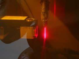 Die Qualität der Düsenöffnung wird indirekt durch Analyse der Raman-Strahlung erfasst; links der Sensor, rechts der durch das Laserschutzfenster rot erscheinende „LMJ“-Strahl.