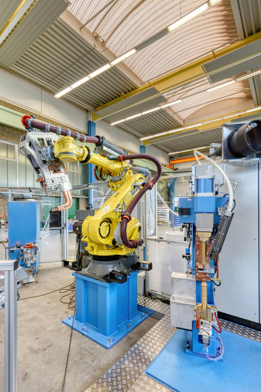 Ein Handling-Roboter führt das Bauteil zu einem DALEX-C-Modul. Dort werden die Rundschweißmuttern zugeführt und automatisch mittels Buckelschweißen auf dem Bauteil fixiert. - © DALEX GmbH & Co. KG